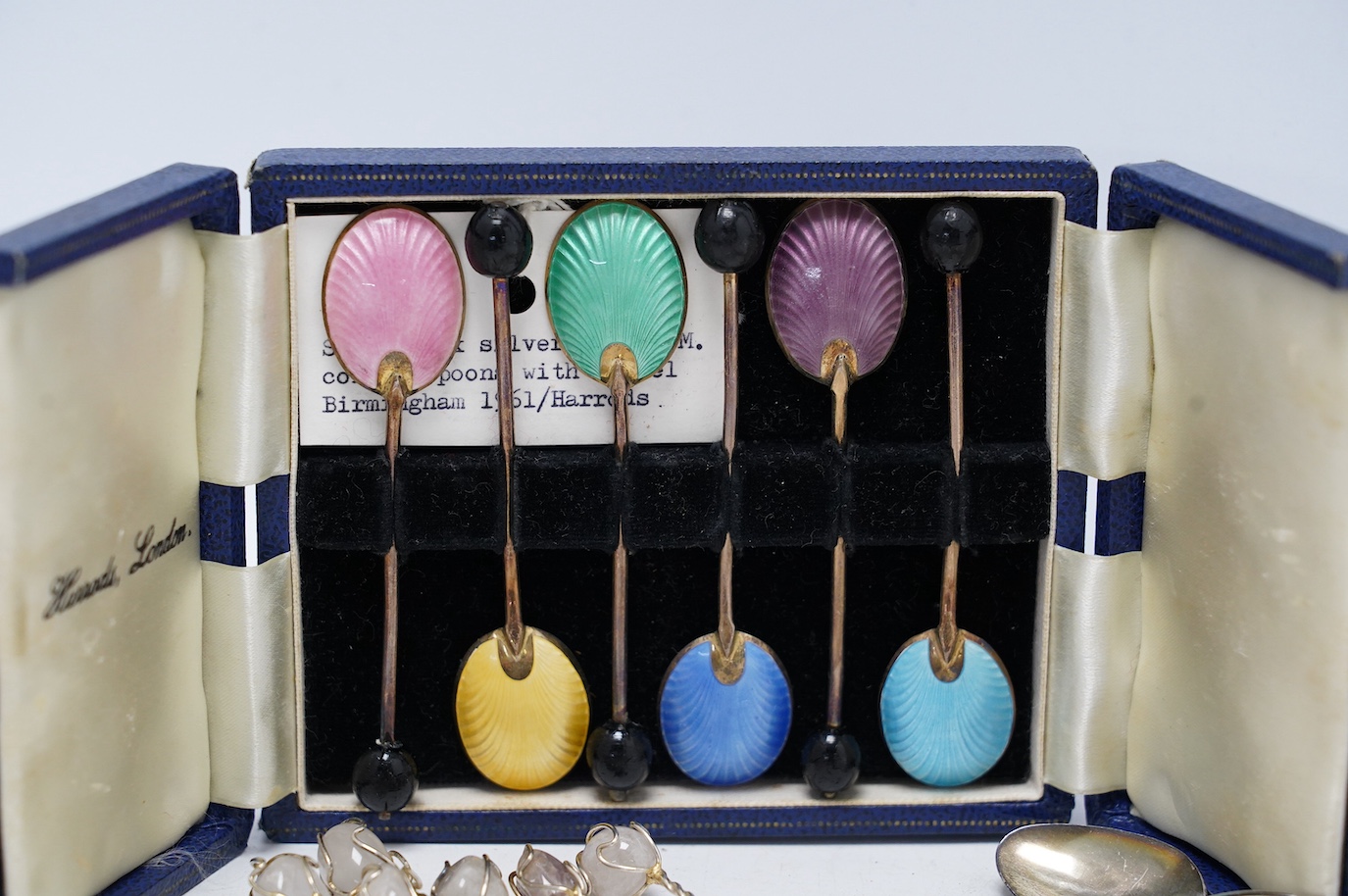 A set of ten George V silver coffee spoons, Birmingham, 1931, a later cased set of six silver and polychrome enamel bean end coffee spoons, a turquoise set sterling spoon, and a set of six white metal spoons with hardsto